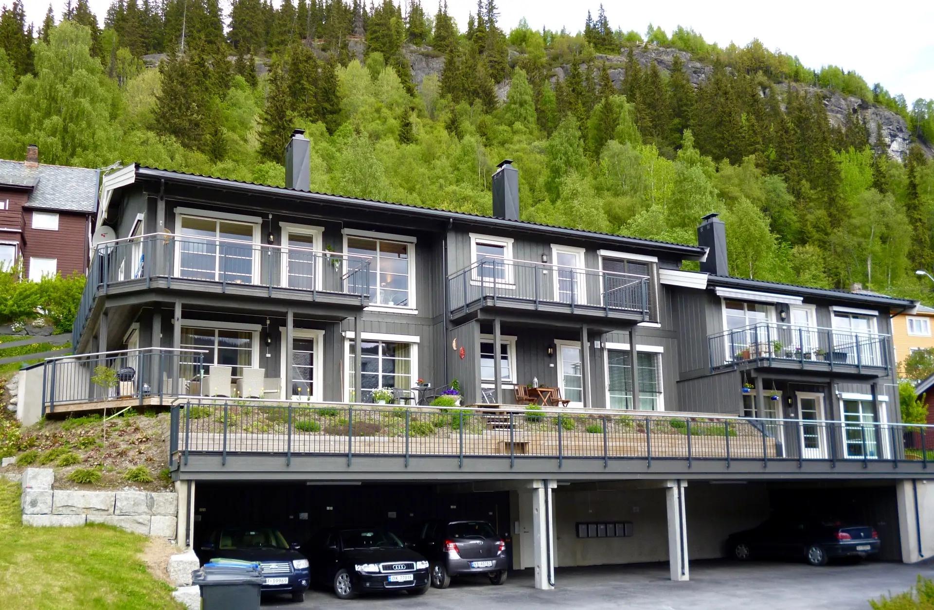 A block of flats in grey with balconies and garages underneath