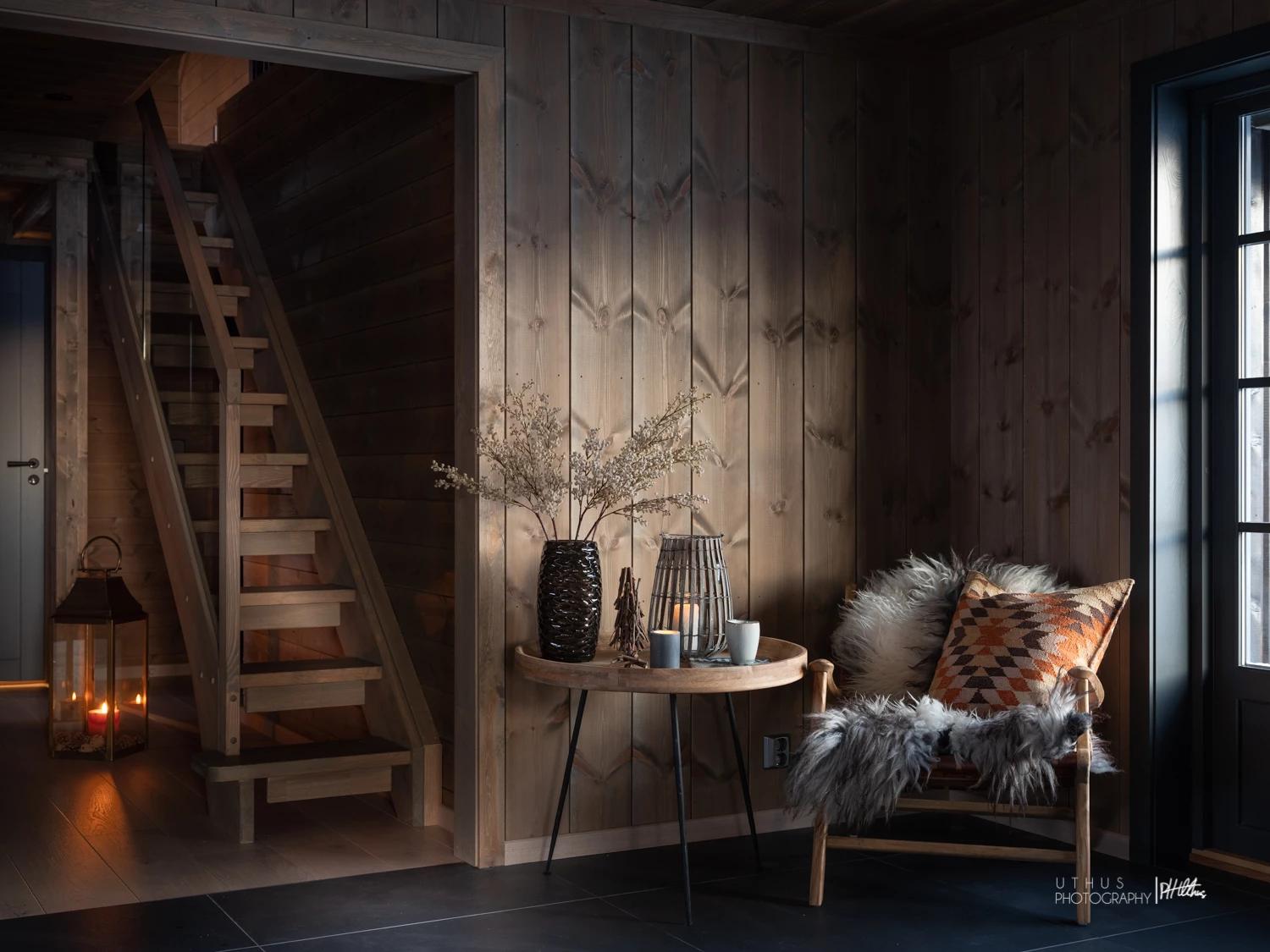 A dark-panelled cabin room with a wooden stair and a lit lantern