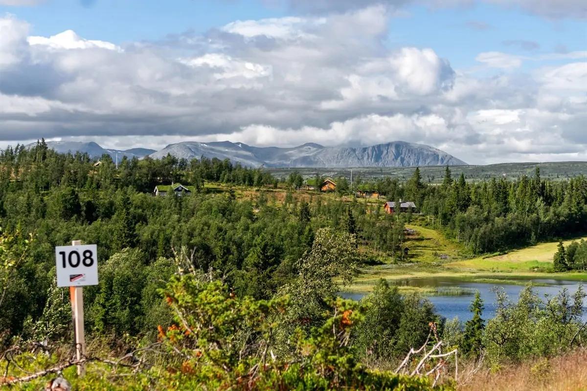 A building plot marked with a numbered post, a lake and mountains behind