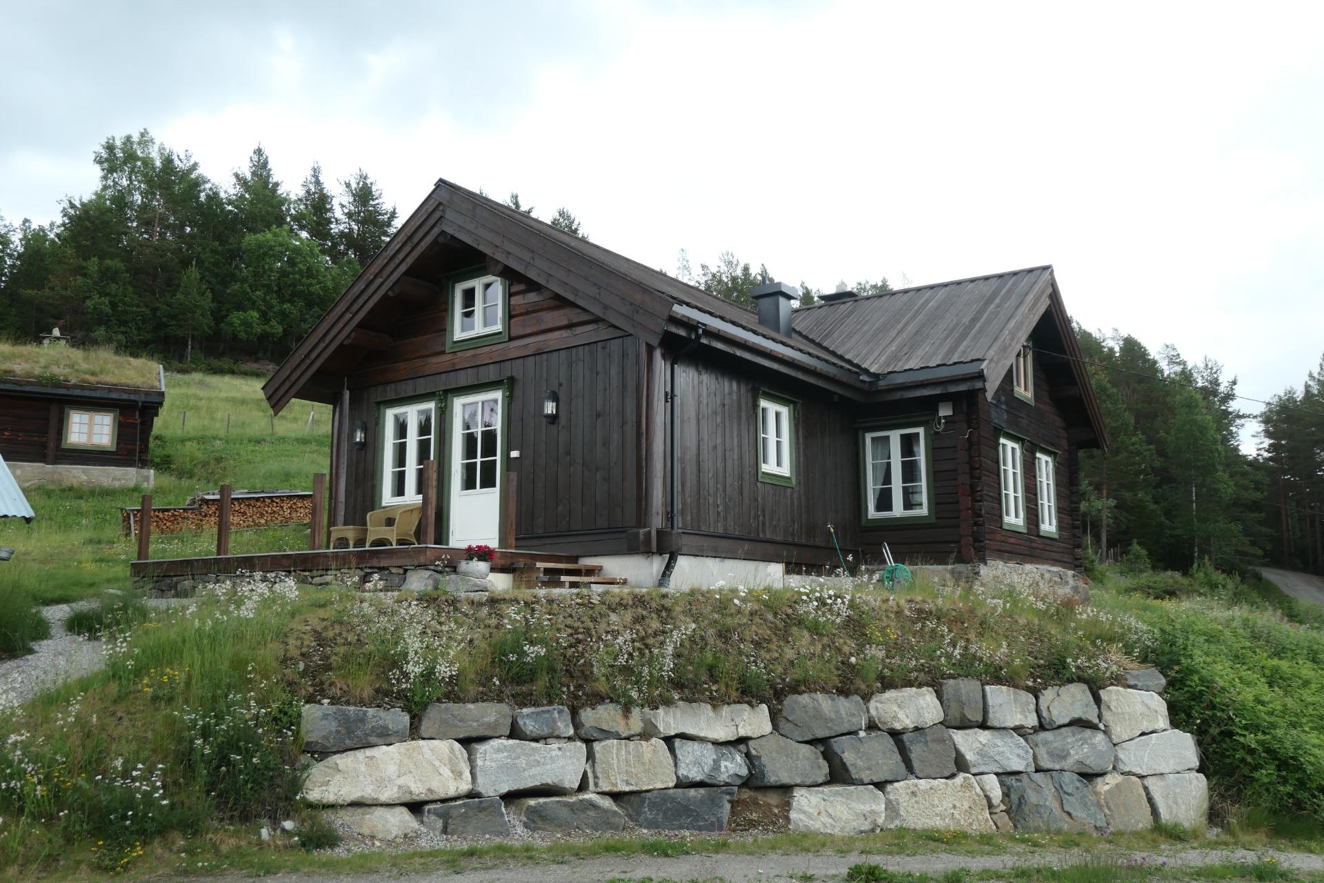 A dark cabin above a dry-stone wall