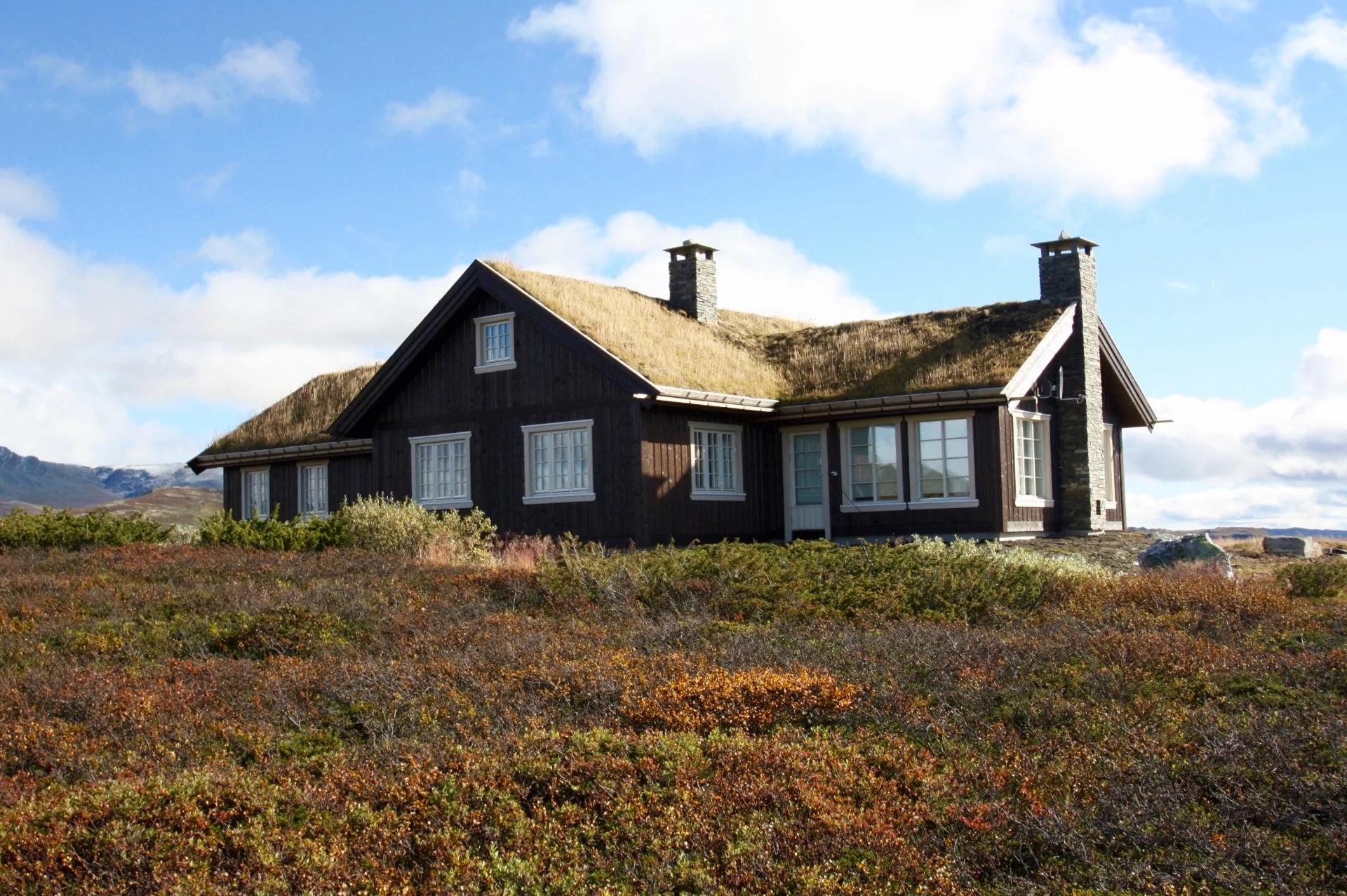 A dark cabin with a turf roof on the open fell